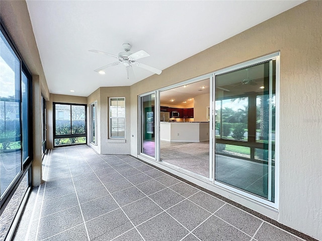 unfurnished sunroom featuring ceiling fan