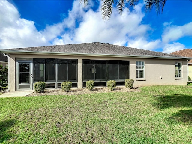 rear view of property featuring a sunroom, a lawn, and stucco siding