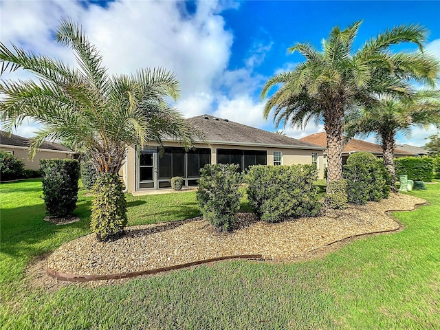 back of house featuring a sunroom, a yard, and stucco siding