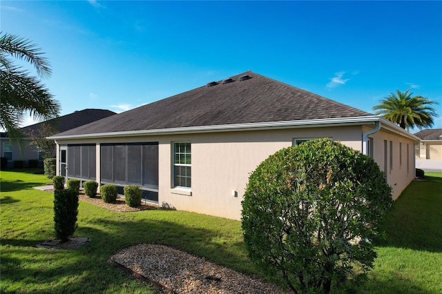 view of side of property with a shingled roof, a lawn, and stucco siding