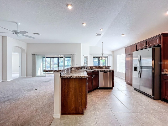 1338 Neuport Path, The Villages, FL 32163 - kitchen with stainless steel appliances, a sink, a textured ceiling, a ceiling fan, and dark stone counters