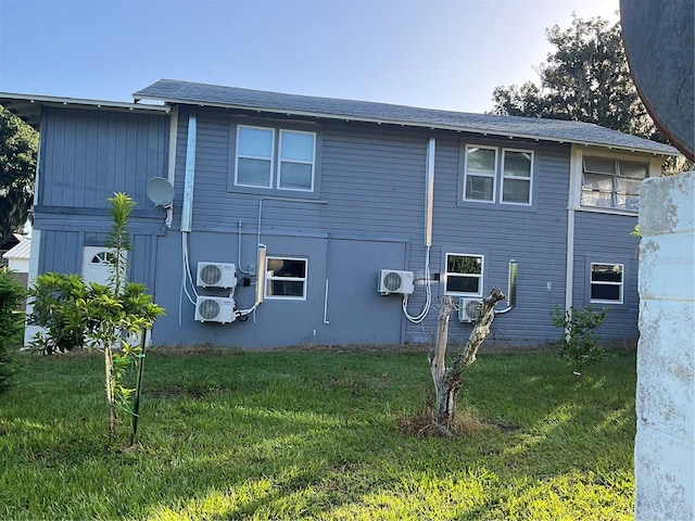 rear view of property with ac unit and a yard