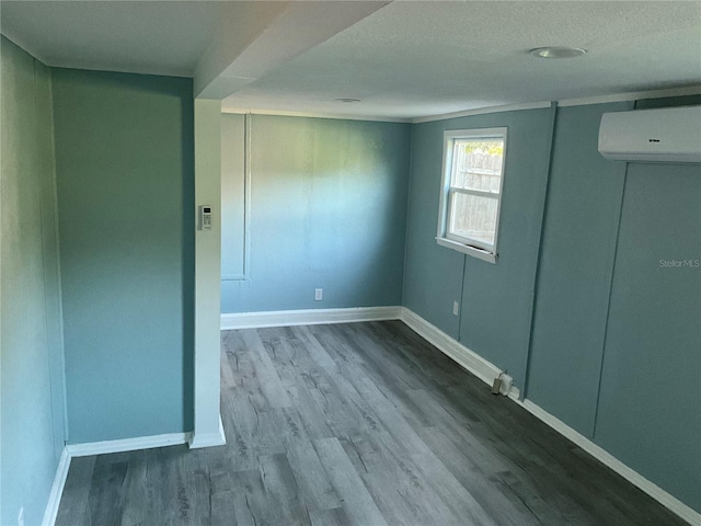 empty room with a textured ceiling, wood-type flooring, and an AC wall unit