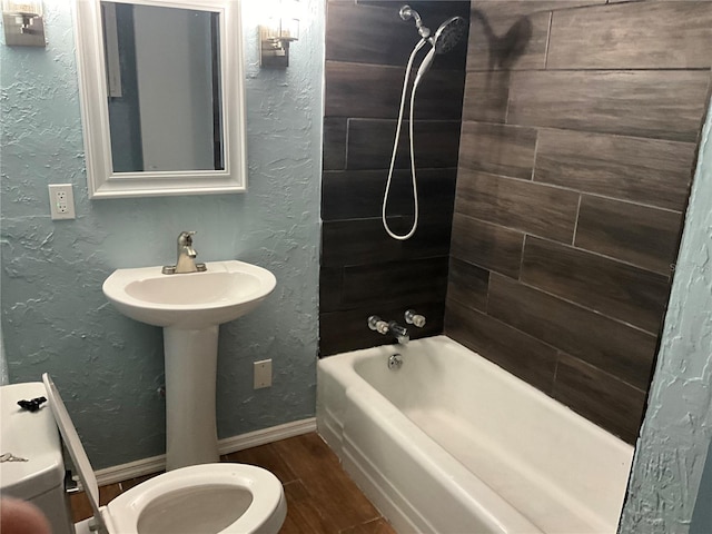 bathroom featuring tiled shower / bath, toilet, and hardwood / wood-style flooring