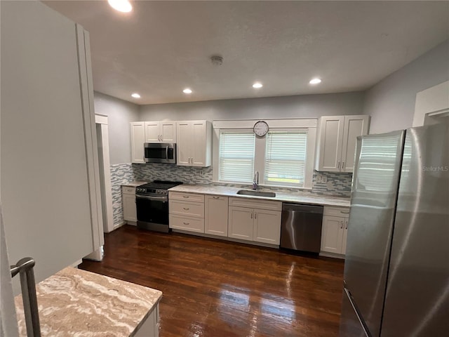 kitchen with white cabinets, appliances with stainless steel finishes, dark hardwood / wood-style flooring, sink, and tasteful backsplash