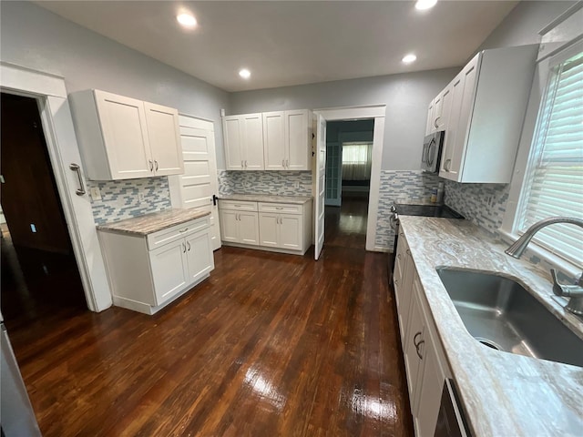 kitchen with white cabinetry, light stone counters, sink, decorative backsplash, and dark hardwood / wood-style floors