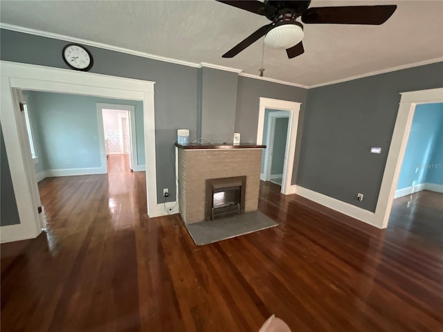 unfurnished living room with ornamental molding, dark hardwood / wood-style flooring, ceiling fan, and a stone fireplace