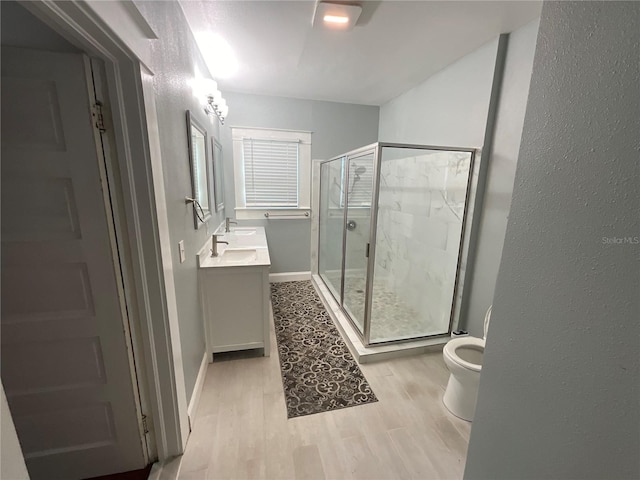 bathroom featuring vanity, toilet, hardwood / wood-style flooring, and a shower with shower door