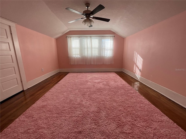 bonus room with a textured ceiling, ceiling fan, dark hardwood / wood-style floors, and vaulted ceiling