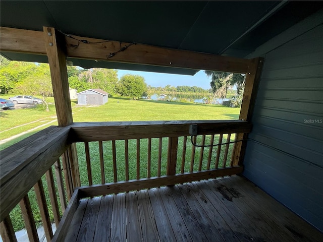 deck featuring a water view, a lawn, and a shed