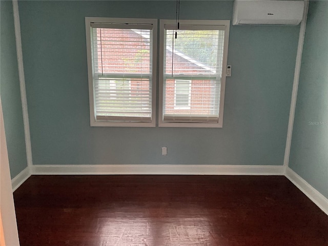 empty room featuring a wall mounted AC and dark hardwood / wood-style flooring