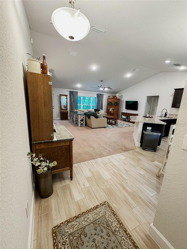 living room featuring lofted ceiling, light hardwood / wood-style floors, and ceiling fan