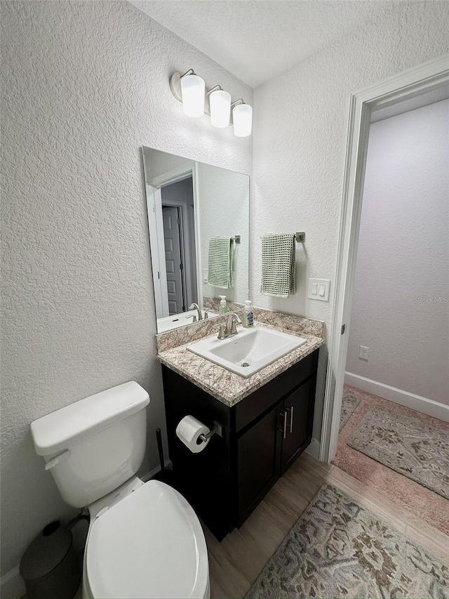 bathroom with vanity, toilet, and hardwood / wood-style floors