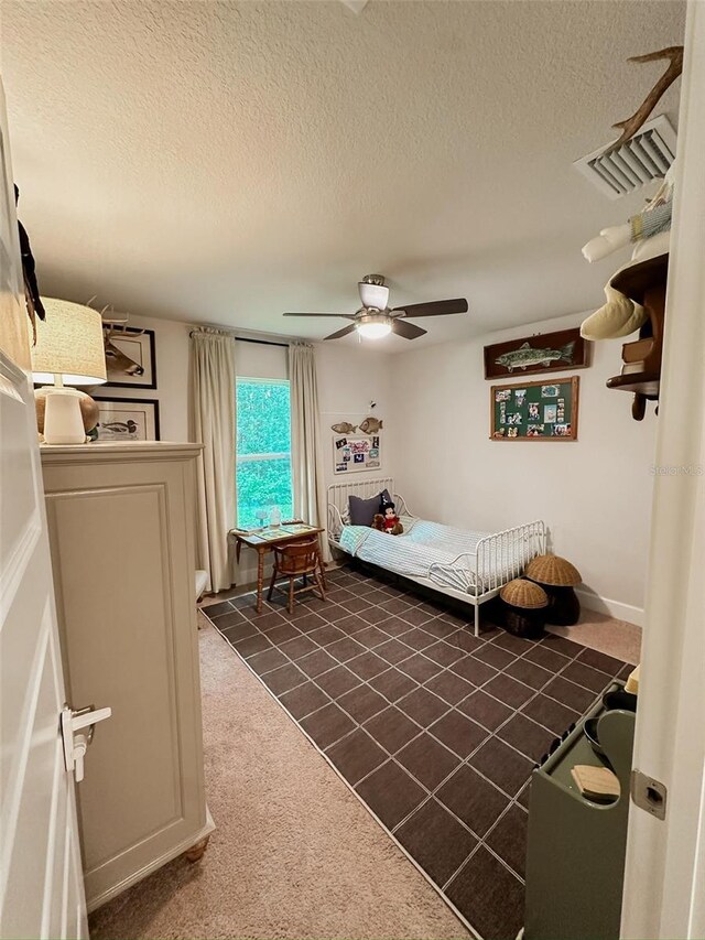 carpeted bedroom featuring ceiling fan and a textured ceiling