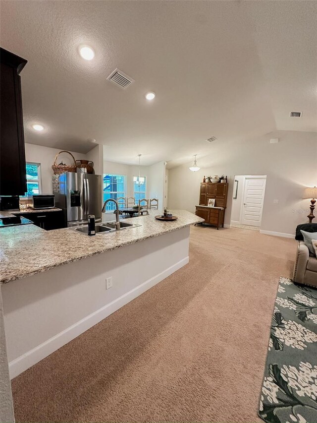 kitchen with carpet flooring, sink, light stone counters, stainless steel fridge with ice dispenser, and a textured ceiling