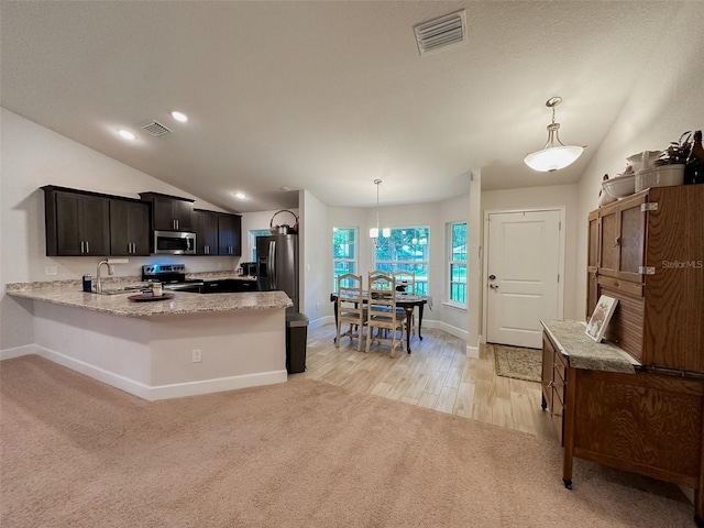 kitchen with decorative light fixtures, vaulted ceiling, stainless steel appliances, and kitchen peninsula