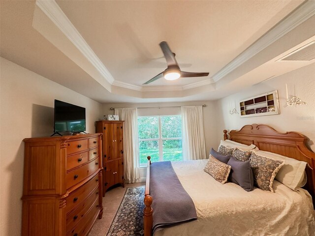 carpeted bedroom with ornamental molding, ceiling fan, and a tray ceiling