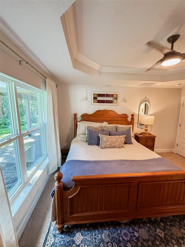 bedroom with crown molding, ceiling fan, a raised ceiling, and dark colored carpet