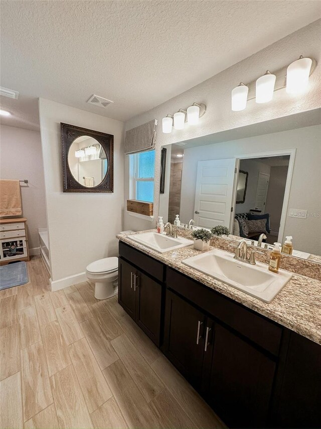 bathroom with hardwood / wood-style floors, vanity, a shower, a textured ceiling, and toilet