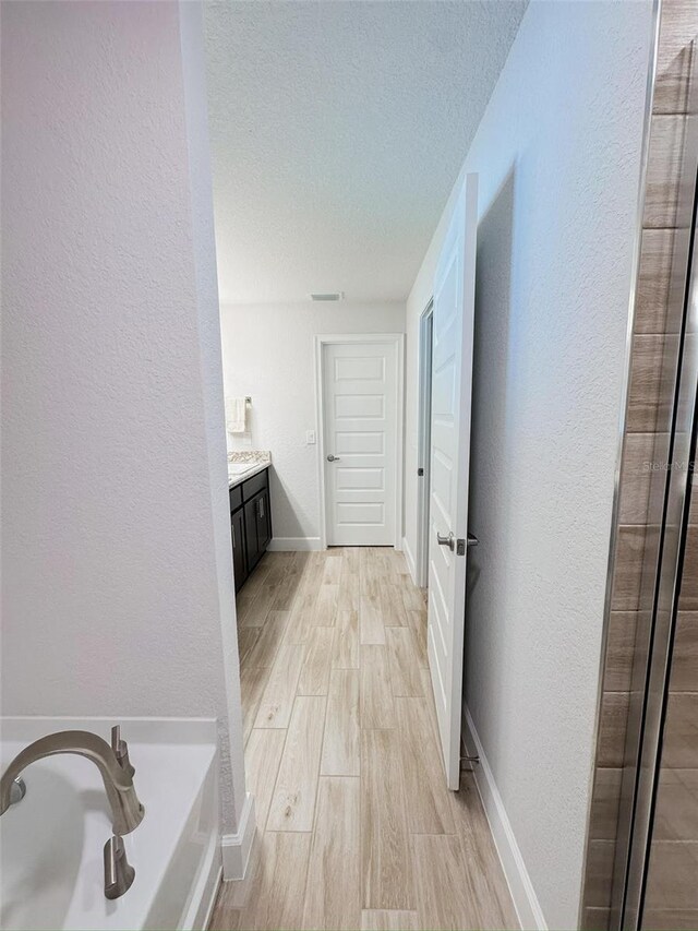 bathroom featuring vanity, a bath, hardwood / wood-style flooring, and a textured ceiling