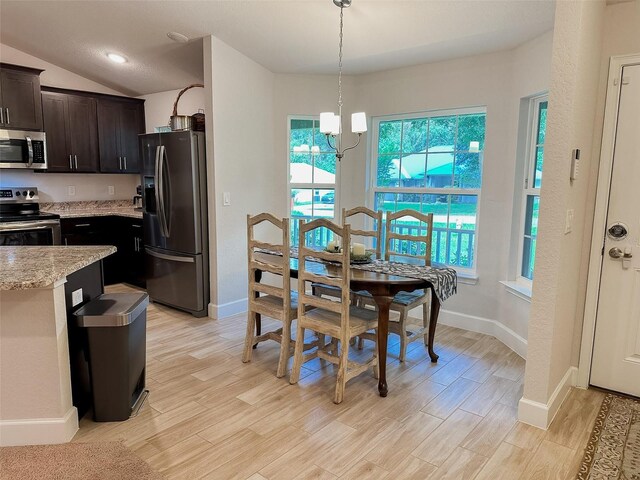 dining area with lofted ceiling, a notable chandelier, and light hardwood / wood-style floors