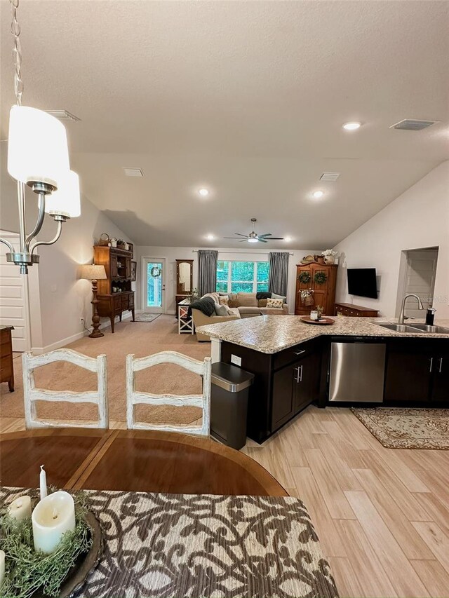 kitchen with sink, vaulted ceiling, stainless steel dishwasher, and light wood-type flooring