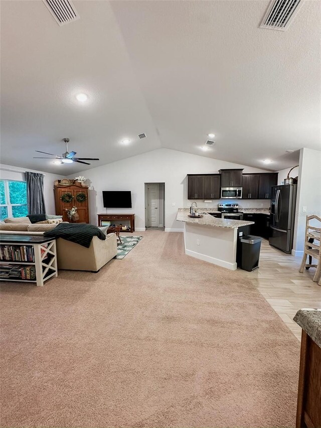 living room with lofted ceiling, sink, ceiling fan, light carpet, and a textured ceiling