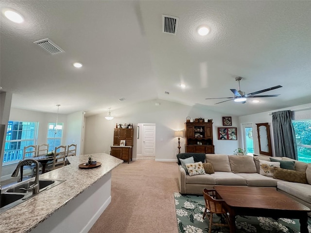 living room featuring light carpet, sink, a wealth of natural light, and vaulted ceiling