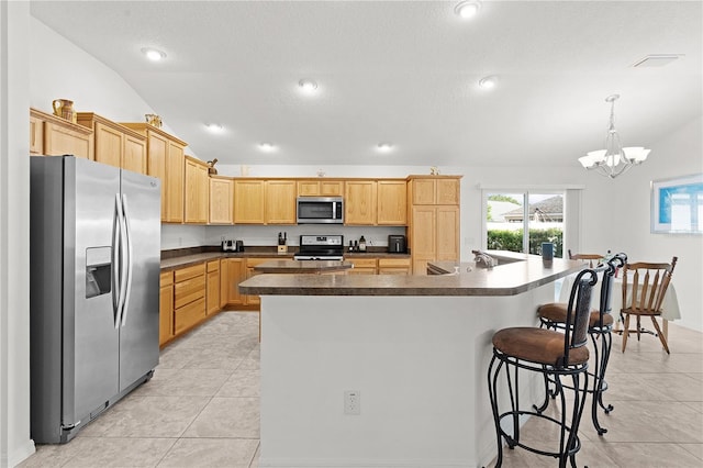 kitchen featuring appliances with stainless steel finishes, light tile patterned flooring, a center island, vaulted ceiling, and decorative light fixtures