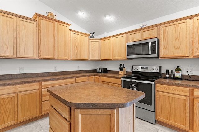 kitchen featuring vaulted ceiling, appliances with stainless steel finishes, light tile patterned flooring, and a kitchen island