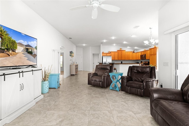 living room with light tile patterned flooring, vaulted ceiling, and ceiling fan with notable chandelier