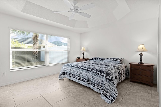 bedroom with a tray ceiling, light tile patterned floors, and multiple windows