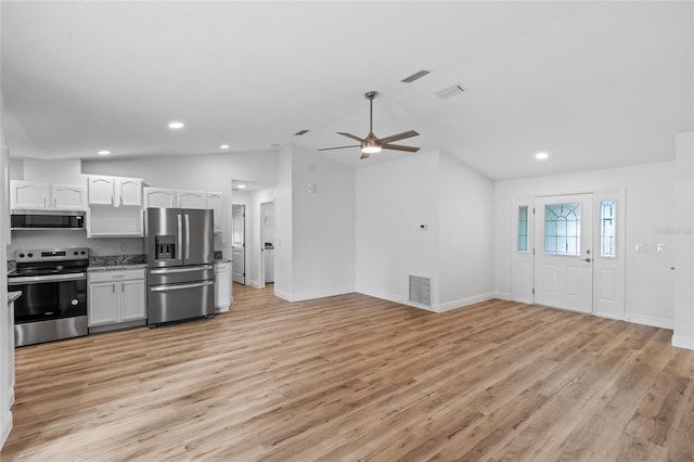 kitchen featuring white cabinetry, stainless steel appliances, light hardwood / wood-style floors, and vaulted ceiling