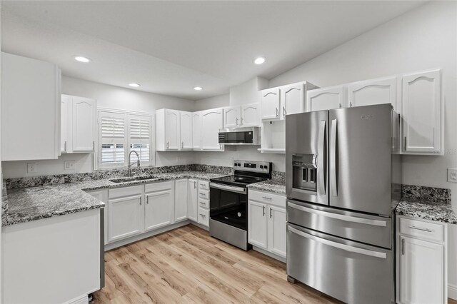 kitchen featuring white cabinetry, appliances with stainless steel finishes, sink, and vaulted ceiling