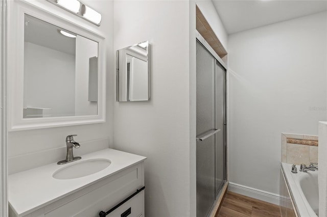 bathroom featuring hardwood / wood-style floors, vanity, and plus walk in shower