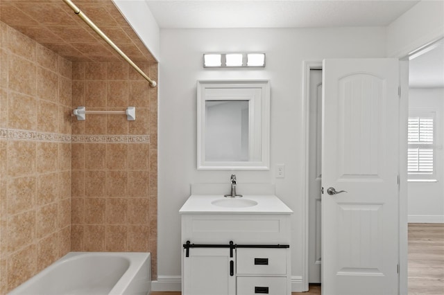 bathroom with hardwood / wood-style floors, vanity, and tiled shower / bath combo