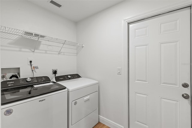 washroom with light hardwood / wood-style floors and washer and dryer