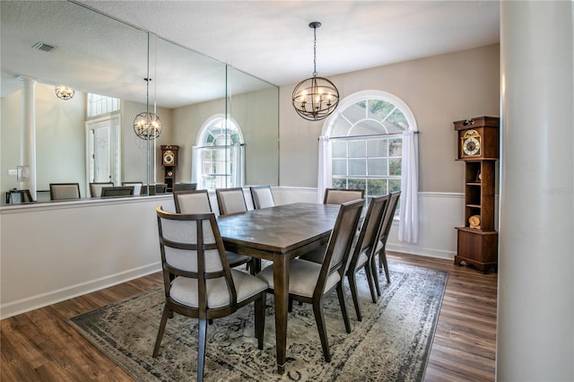 dining space with dark hardwood / wood-style flooring, decorative columns, a textured ceiling, and a notable chandelier