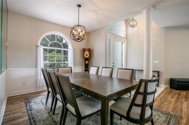 dining area featuring decorative columns, dark wood-type flooring, and a chandelier