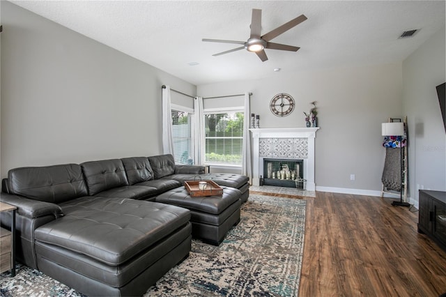 living room featuring a textured ceiling, a fireplace, ceiling fan, and dark hardwood / wood-style floors