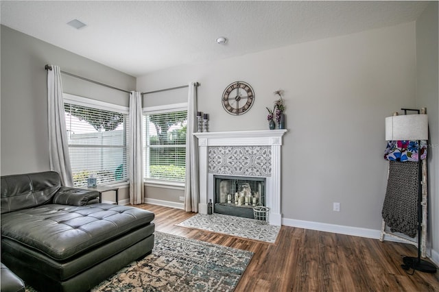 living room with a textured ceiling, a tiled fireplace, and hardwood / wood-style floors