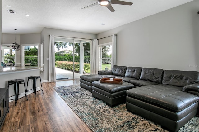 living room featuring ceiling fan, a textured ceiling, and dark hardwood / wood-style flooring