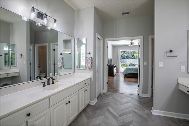 bathroom with vanity, ceiling fan, parquet flooring, toilet, and a textured ceiling