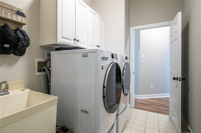 clothes washing area with cabinets, separate washer and dryer, sink, and light tile patterned floors