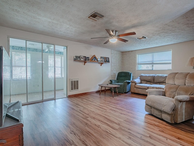 living room with light hardwood / wood-style floors, a textured ceiling, and ceiling fan