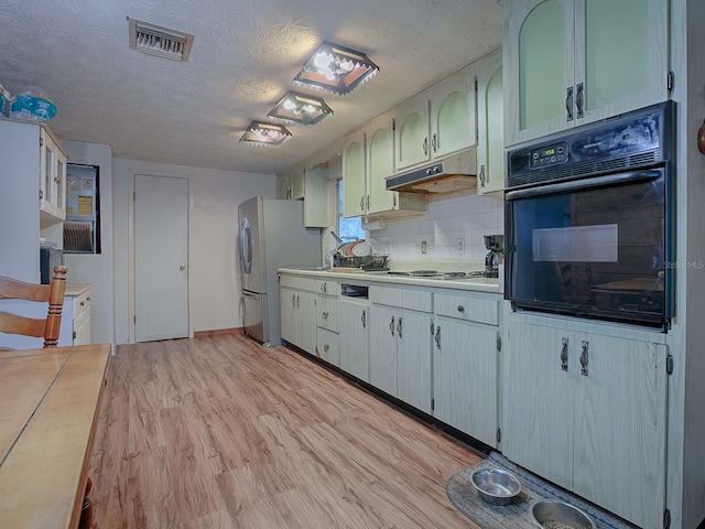 kitchen with stainless steel appliances, tasteful backsplash, light wood-type flooring, and a textured ceiling