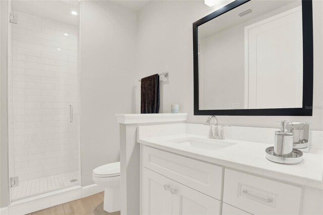 bathroom featuring a shower with shower door, toilet, and vanity