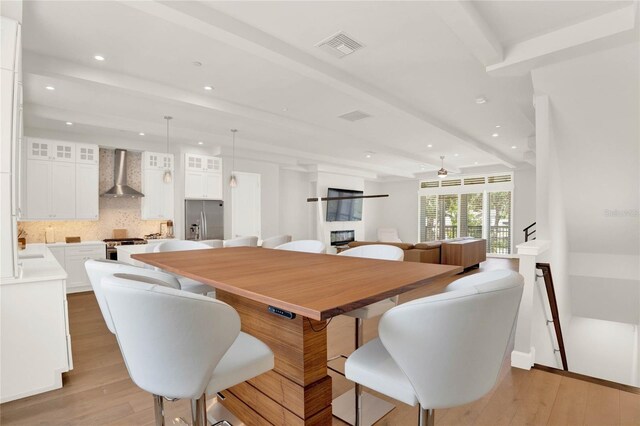 dining space with beam ceiling and light wood-type flooring