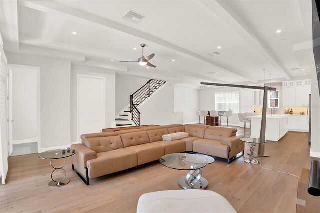 living room with sink, light wood-type flooring, ceiling fan, and beam ceiling