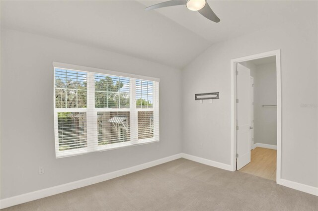 spare room featuring light carpet, vaulted ceiling, and ceiling fan